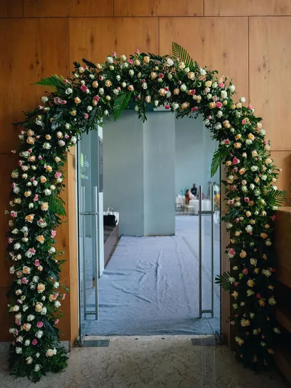 A lush floral archway serves as the entrance to the Mehendi hall, welcoming guests into the transformed space.