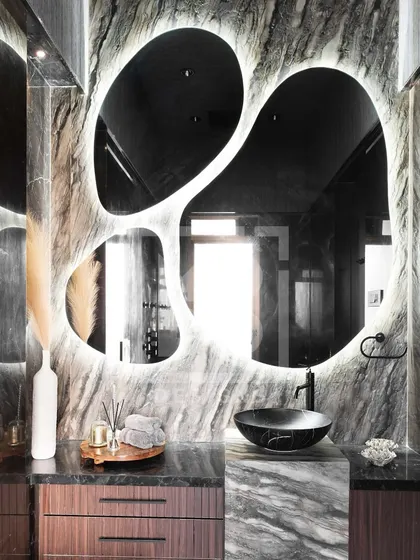 Another example of a statement mirror. The organic, free-form shape with backlighting creates a dramatic and artistic focal point in this modern bathroom.