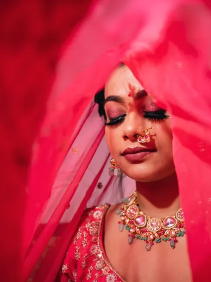 An artistic shot of the bride with her eyes closed, enveloped in her vibrant red dupatta.
