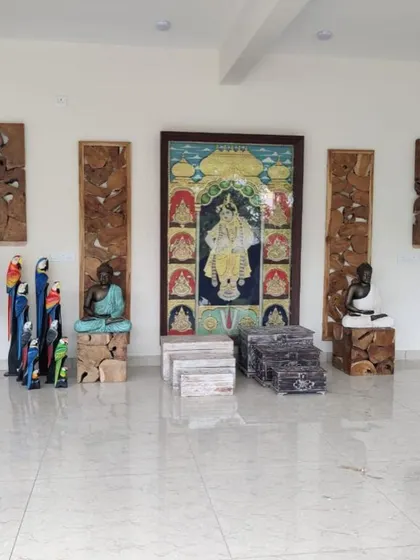 A display of various decorative items, including wooden parrot statues, a Buddha on a wooden block, and traditional Indian paintings.