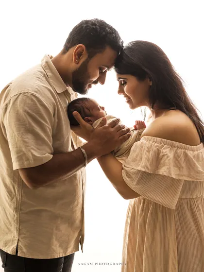 A new family gazes at their precious newborn. This high-key portrait, with its soft lighting and neutral tones, feels pure, gentle, and full of love.