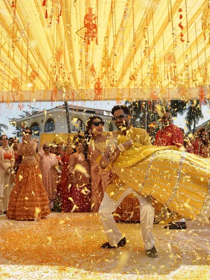 The groom lifting the bride amidst a shower of flower petals. A truly cinematic and fun moment from their Goa Haldi.