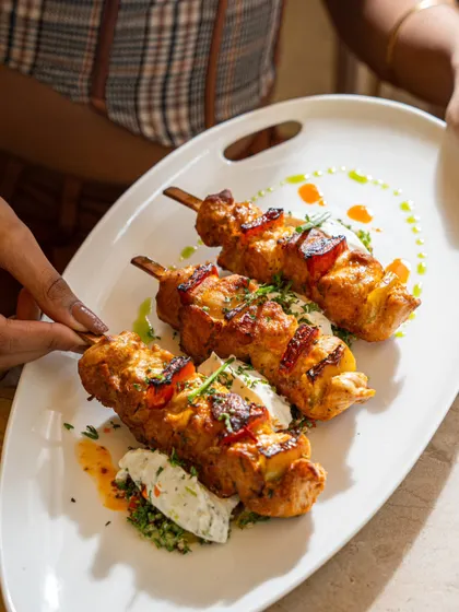 A lifestyle shot of chicken skewers being served. Including hands and human interaction makes the food feel more accessible and engaging.