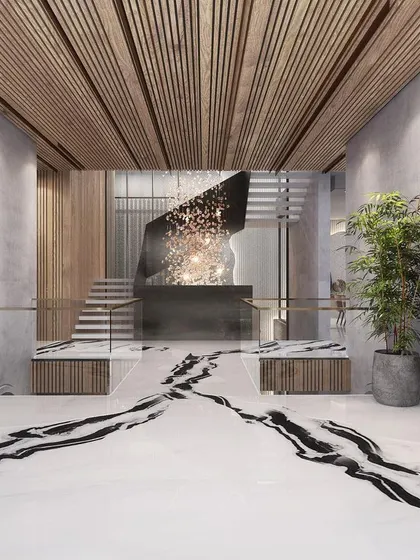 This foyer for a repeat client features dramatic black-veined marble flooring that acts as a pathway, guiding you toward a sculptural staircase. The design blends raw concrete textures with warm wood and bold art.