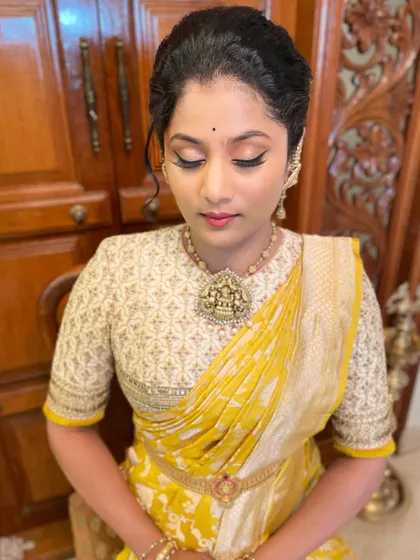 A close-up of the makeup for this client. The eyes are softly defined, and the skin is glowing, perfectly complementing her yellow and white saree.