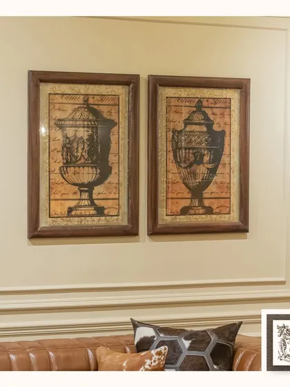 This pair of wall art prints featuring classical decorative urns adds a touch of historical elegance. The vintage-inspired design and dark frames make them a sophisticated addition above a leather sofa.