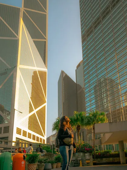 Looking up at the impressive Bank of China Tower during golden hour. The warm light reflecting off the glass and steel creates a beautiful, glowing effect.