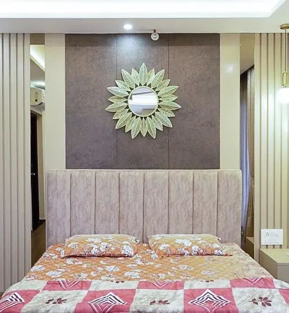 This bedroom at Pashmina Waterfront focuses on timeless elements like vertical fluted paneling and a soft, muted palette. The sunflower-shaped mirror adds a touch of personality.
