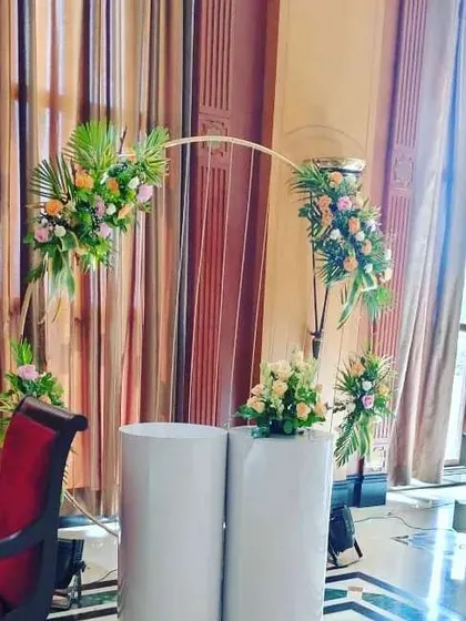Another modern decor idea, this one features a floral semi-arch placed on top of white pedestals. It's a clean and stylish setup that can be used for a cake table or as part of the stage decor.