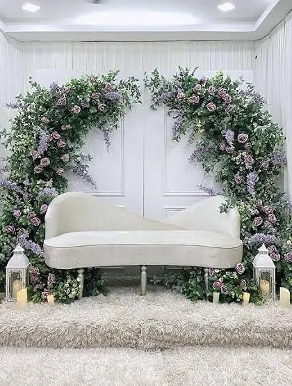 For a touch of classic elegance, we designed this stunning backdrop featuring a white chaise lounge set against a dramatic arch of purple flowers and greenery. The lanterns and candles add a soft, romantic glow.