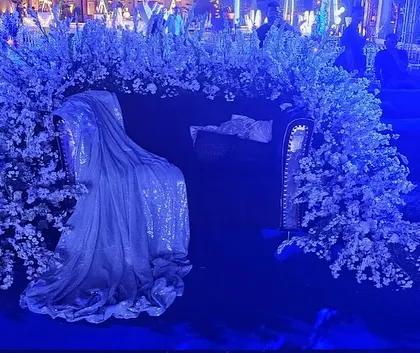 A unique seating idea for the celestial sangeet. This couch is draped in shimmery fabric and surrounded by a cloud of white flowers, creating a photo spot that looks like a seat on a cloud.