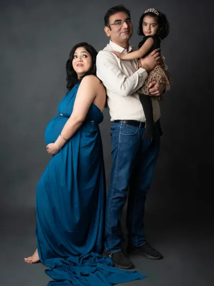 A classic family pose during a maternity shoot, with the older sister excited to welcome the new baby.