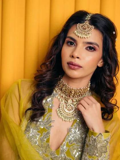 This look, set against a vibrant yellow background, shows how a soft pink eye and defined lip can create a striking contrast for a modern mehendi bride.