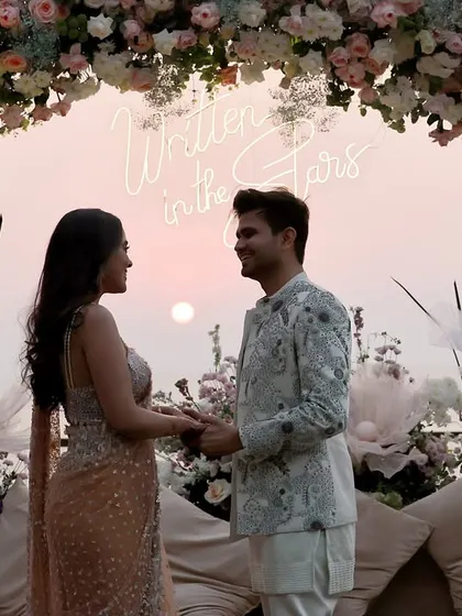 We work to capture the full scale of your event, including the stunning decor. This shot frames the couple against a beautiful floral arch and a "Written in the Stars" neon sign, preserving the ambiance of their special day.