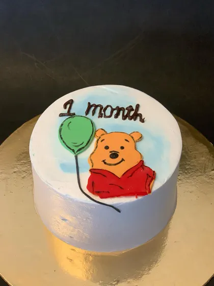 A sweet little bento cake celebrating a baby's one-month milestone. This orange chocolate cake features a hand-piped drawing of Winnie the Pooh.