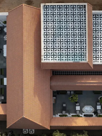 An aerial perspective of the Elgin Cafe, revealing the geometric precision of the layout. The design interlocks the terracotta-tiled roof with a patterned glass skylight and open-air courtyards.