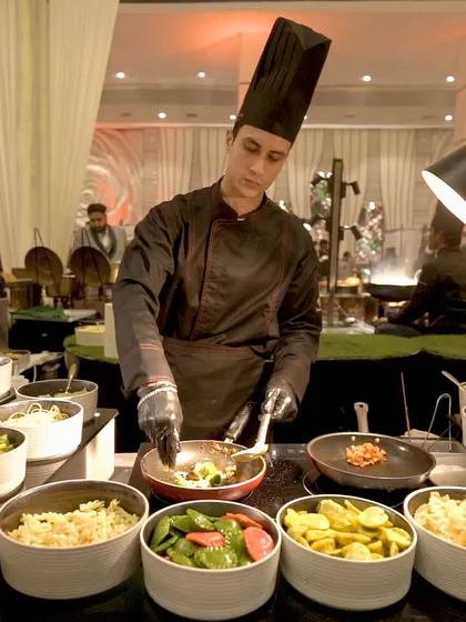 A chef at our live pasta station, stir-frying fresh ingredients. Guests can choose their own vegetables, sauces, and pasta, creating a personalized dish made right before their eyes.