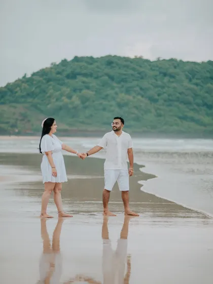 A serene portrait of a couple standing on the wet sand, with their reflection captured in the water.