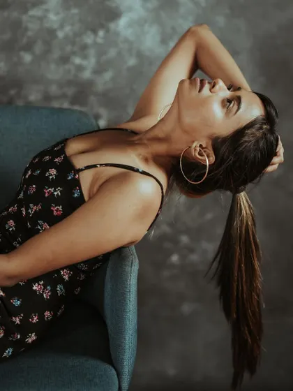 Model in a floral dress reclining on a blue sofa against a textured grey backdrop