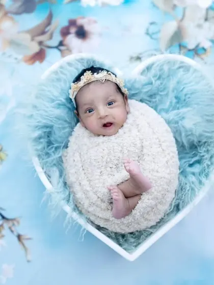 A beautiful one-month-old angel nestled in a heart-shaped bowl. The soft blue fur and floral background make this a truly lovely portrait.