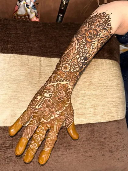 A full-arm design with the initial 'T' prominently featured on the palm, surrounded by a sea of intricate patterns.