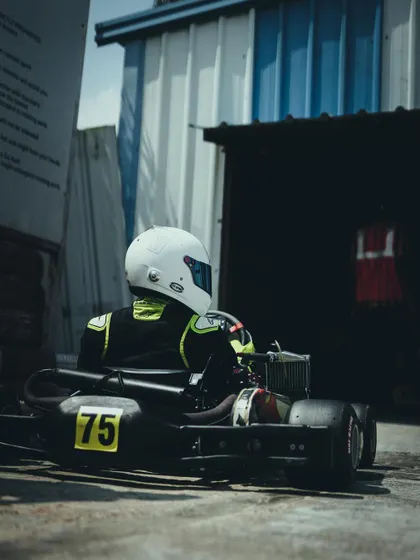 A driver waiting in his kart in the pit area.