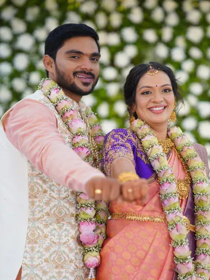 A happy couple on their engagement day. The bride's makeup is soft and romantic, with a lovely pink saree and coordinated flower garlands.