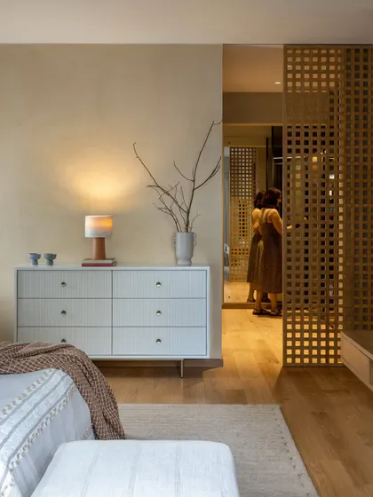 A wooden lattice screen provides a beautiful, textural separation between the bedroom and the walk-in closet. The reflection in the mirror adds depth and interest to the space.