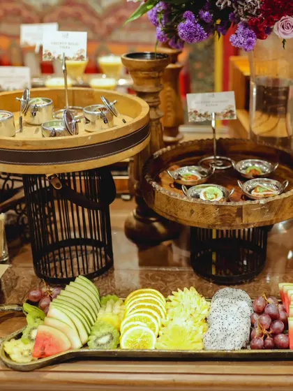 An elegant grazing table setup for a formal event, featuring a mix of our Indian fusion appetizers and a beautifully arranged fresh fruit platter with watermelon, kiwi, and grapes.