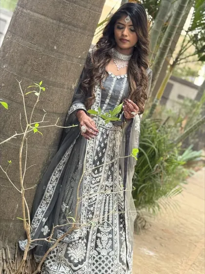 A thoughtful pose in the grey and white embroidered lehenga, set against a natural backdrop. The contrast of the embroidery is striking.