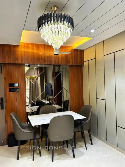 A luxurious dining area setup. The combination of a wood-paneled wall, a large mirrored panel, and a stunning crystal chandelier creates a perfect ambiance for formal dinners.
