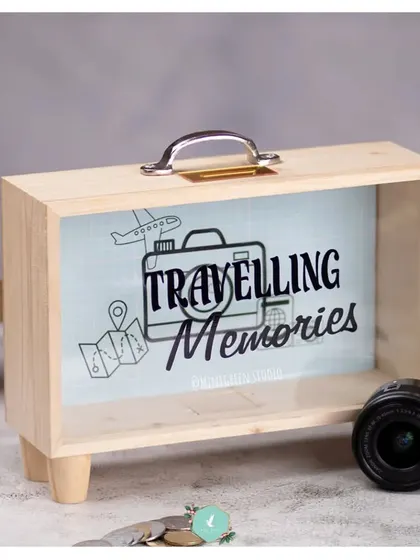 A product shot of our wooden 'Travelling Memories' savings box. This clear-fronted box lets you watch your savings grow and serves as a fun, decorative reminder of future adventures.