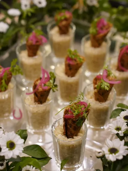 Savory cones filled with a flavorful mixture and topped with pickled onions and fresh dill. These appetizers are served in individual glasses filled with rice, creating a unique and stable presentation that is both practical and beautiful.