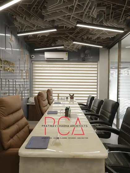 A view of the main conference room at StyleIn Homes, highlighting the interplay of the complex acoustic ceiling, custom CNC-milled wall panels, and luxurious leather seating. The design balances corporate professionalism with bold architectural statements.
