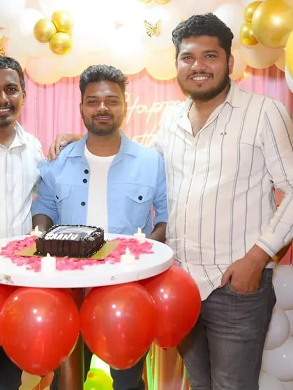 Friends celebrating a birthday, gathered around a cake table.