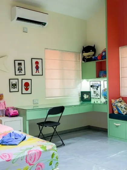 The room is designed with distinct zones for each child, including a study corner with superhero art, showing how I personalize spaces even within a shared room.