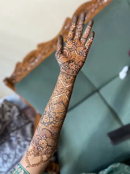 The back of the hand for a bridal set, featuring a continuous pattern that flows from the fingers up the arm. This design uses a mix of geometric and floral elements.