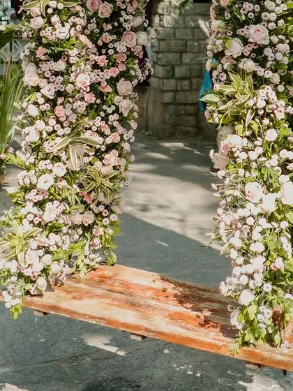 A charming wooden swing is decorated with an abundance of fresh flowers.