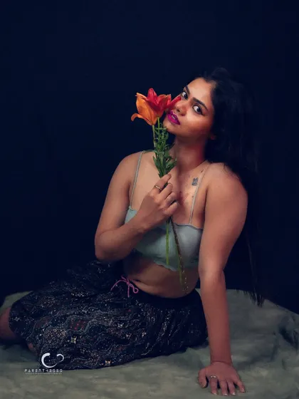 A full-body shot that showcases the contrast between the delicate flowers and her strong, confident pose.