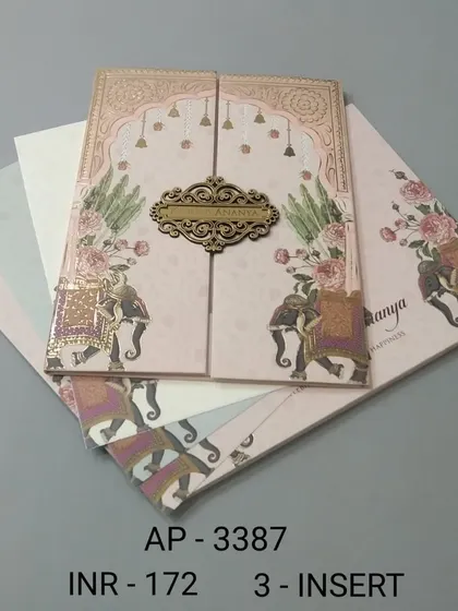 This gate-fold invitation in a soft pink hue is decorated with royal elephants and floral designs. A wooden nameplate holds the card closed, adding a rustic and personal touch.