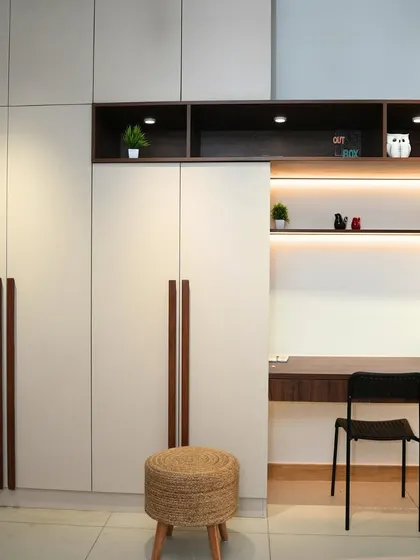 A clever wardrobe design that incorporates a study desk and open shelving. The combination of white and wood-grain finishes, along with integrated lighting, makes this a perfect multi-functional unit.