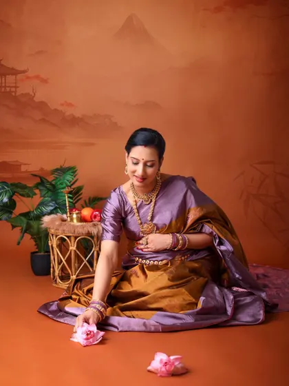 A graceful solo portrait with a traditional theme. The mom-to-be is seated on the floor, reaching for a lotus flower, against a backdrop of a classic Indian painting.