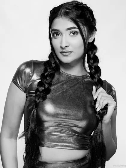 A black and white portrait of a model in a metallic pink top and braided pigtails. The monochrome conversion gives this fun, modern look a classic, high-fashion edge.