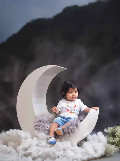 A dramatic take on our celestial theme, with a darker, cloud filled sky. The moon prop provides the perfect seat for this little explorer during his toddler photoshoot.