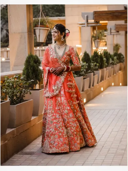 A full-length portrait of the bride in a gorgeous orange lehenga.