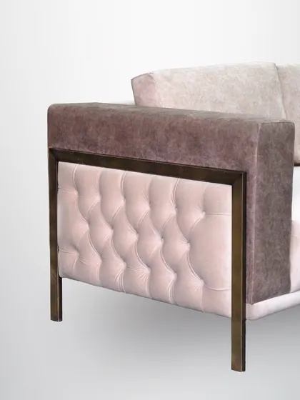 A detail of a modern sofa, showing the tufted leather side panel set within a sleek metal frame. This mix of materials creates a sophisticated and urban look.