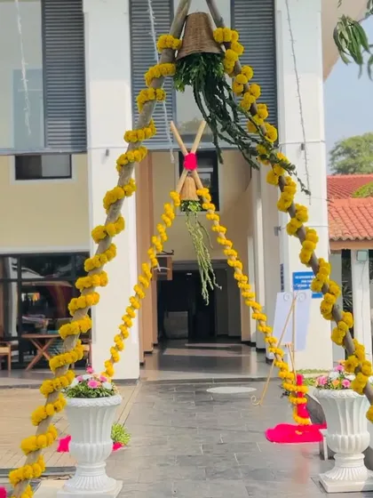 The entrance to the Haldi ceremony, marked by an arch decorated with yellow marigold garlands and a traditional bell. It's a simple and auspicious welcome for the guests.