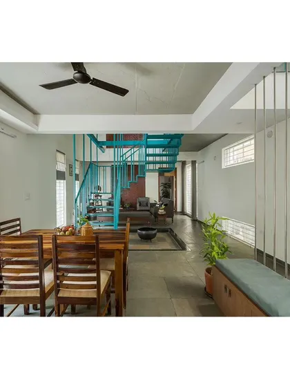 The dining area is positioned centrally within the open plan, adjacent to the staircase and a small internal courtyard. This placement makes it a natural gathering spot, visually connected to the rest of the home's activities.