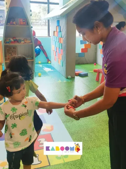 Two children hold hands while a staff member ties on a friendship band. Our Friendship Day event is all about celebrating the bonds between friends.