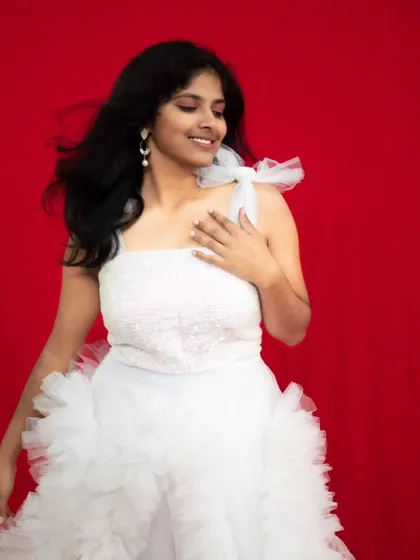 A beautiful studio shot of our white ruffle gown against a vibrant red background.